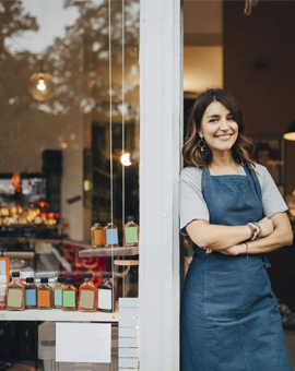 Proud shop owner standing in the doorway of her specialty food store