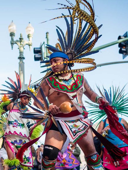 Arts and Culture: dancer in a colorful feathered costume performing at a street festival