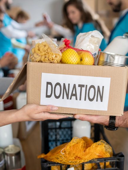 Charities and Giving: volunteers handing over a donation box of groceries