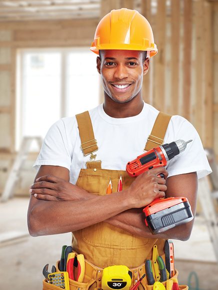 Construction and Trades: smiling tradesman in a hard hat and tool belt holding a drill
