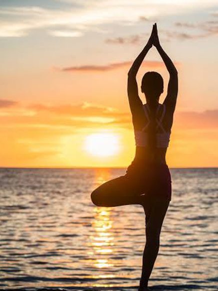 Health and Wellness: woman in a yoga pose on a beach at sunset