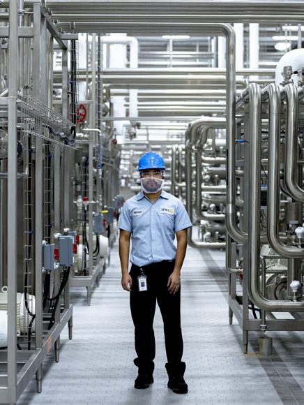 Manufacturing and Industry: worker in safety gear inspecting a factory production line