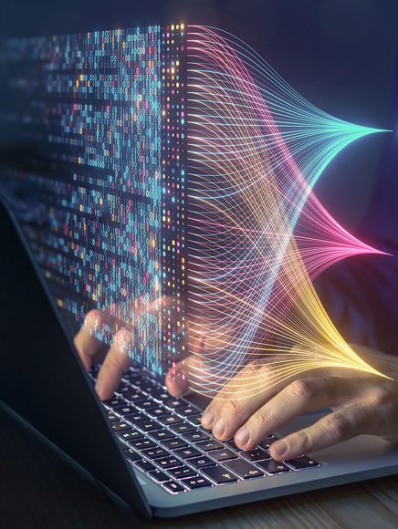 Technology and Technical: hands typing on a laptop surrounded by flowing data